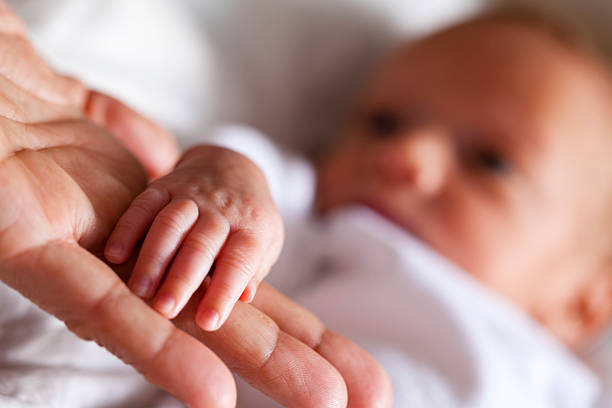 newborn holding mother's hand